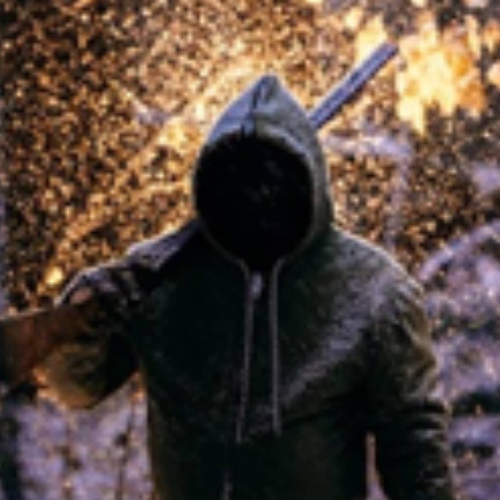 A man with a hoodie and a rifle over his shoulder and fire in the backgroud.